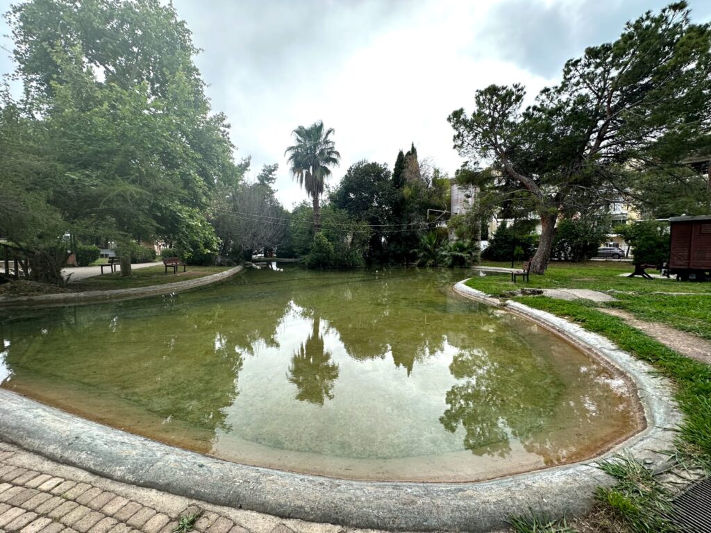 Panoramic view of Kalamata Municipal Railway Park, showcasing vintage trains, well-kept tracks, and lush green spaces, offering a serene and historical setting for visitors.